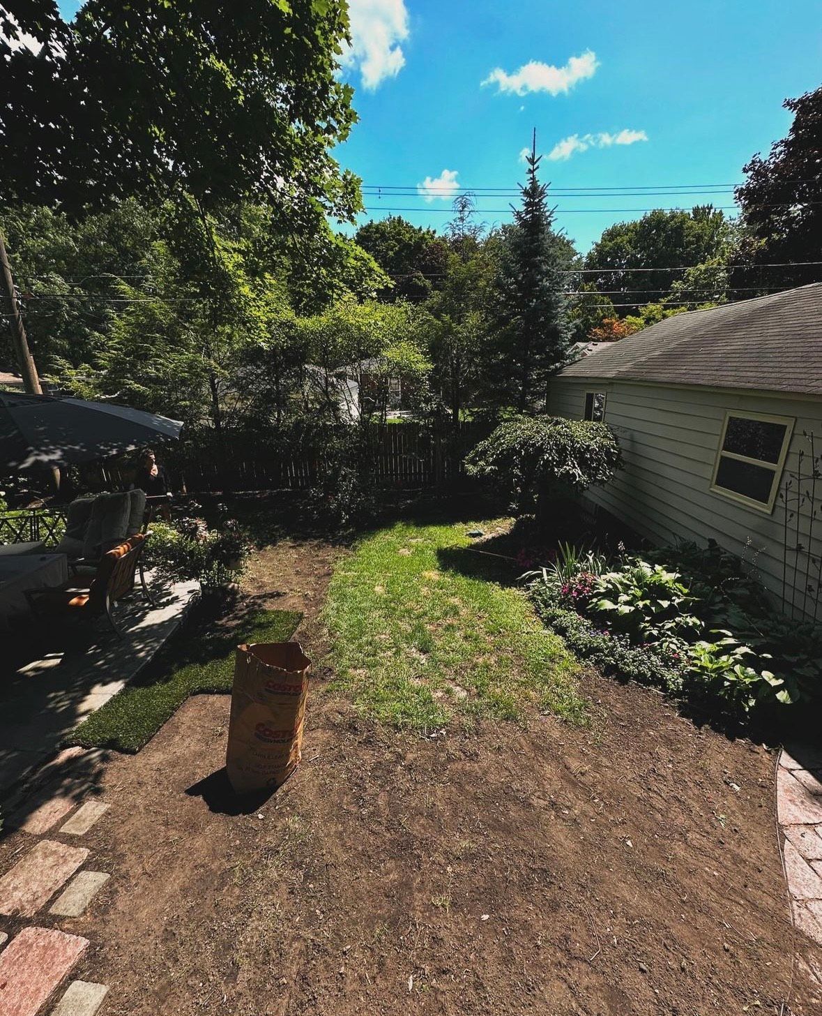 A backyard with a bag of dirt in the middle of it and a house in the background.