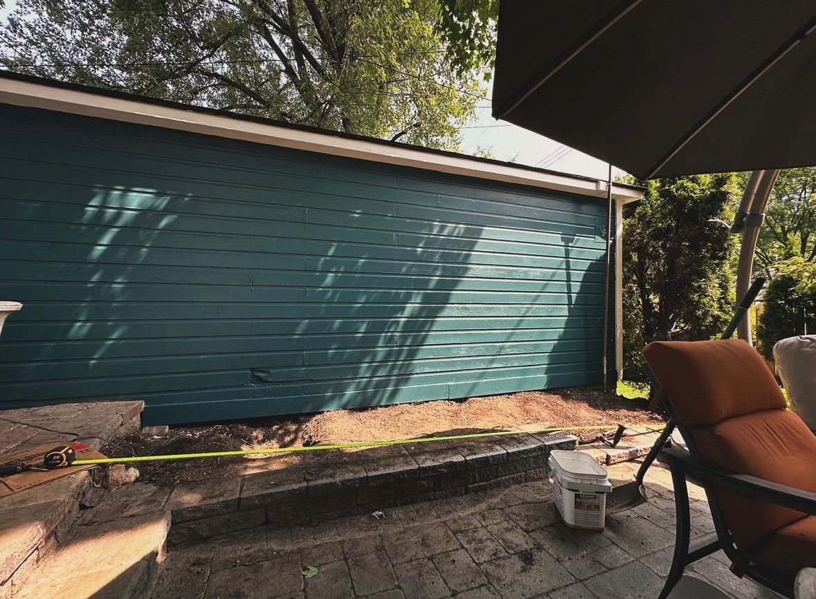 A patio with a chair and umbrella in front of a blue garage door.