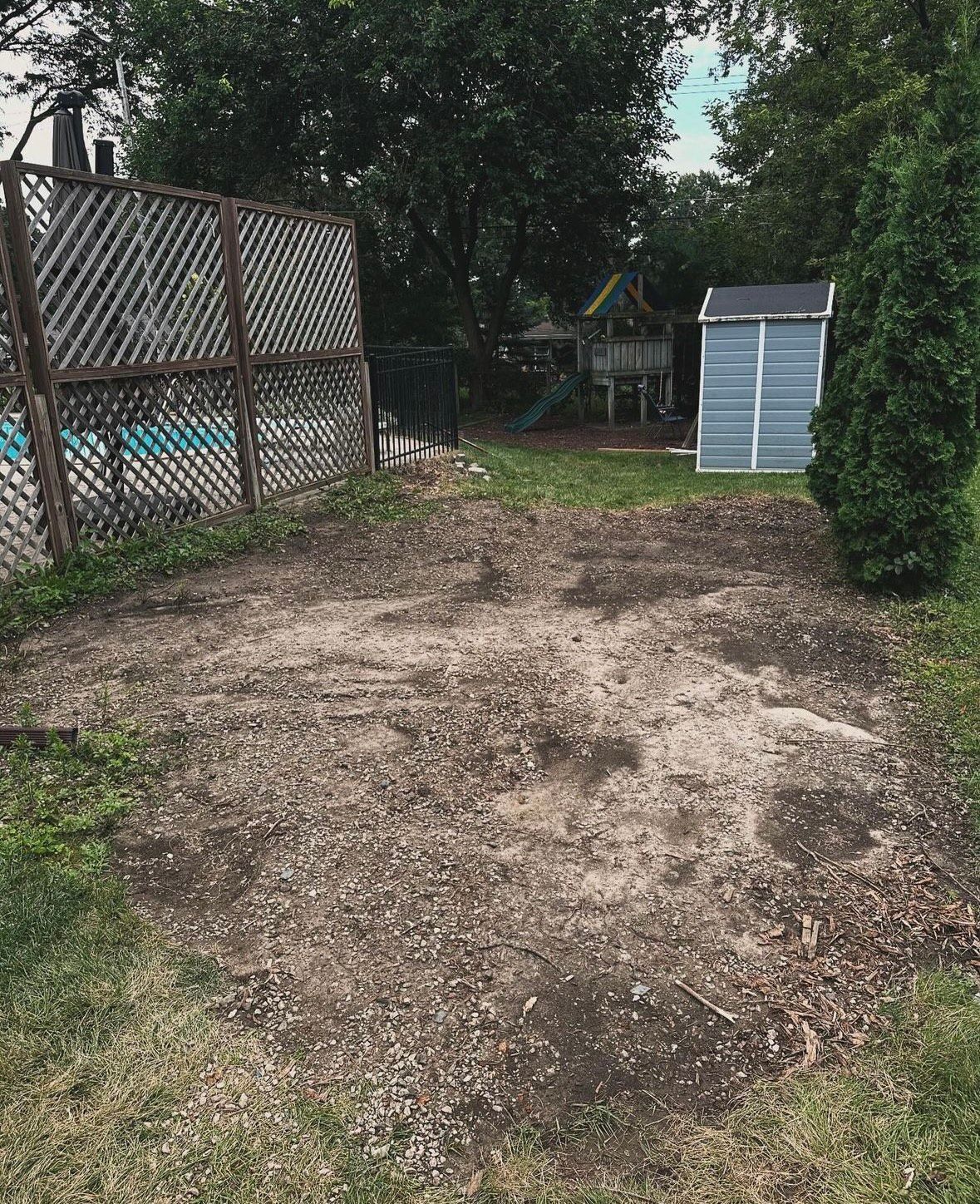 A backyard with a shed and a playground in the background.