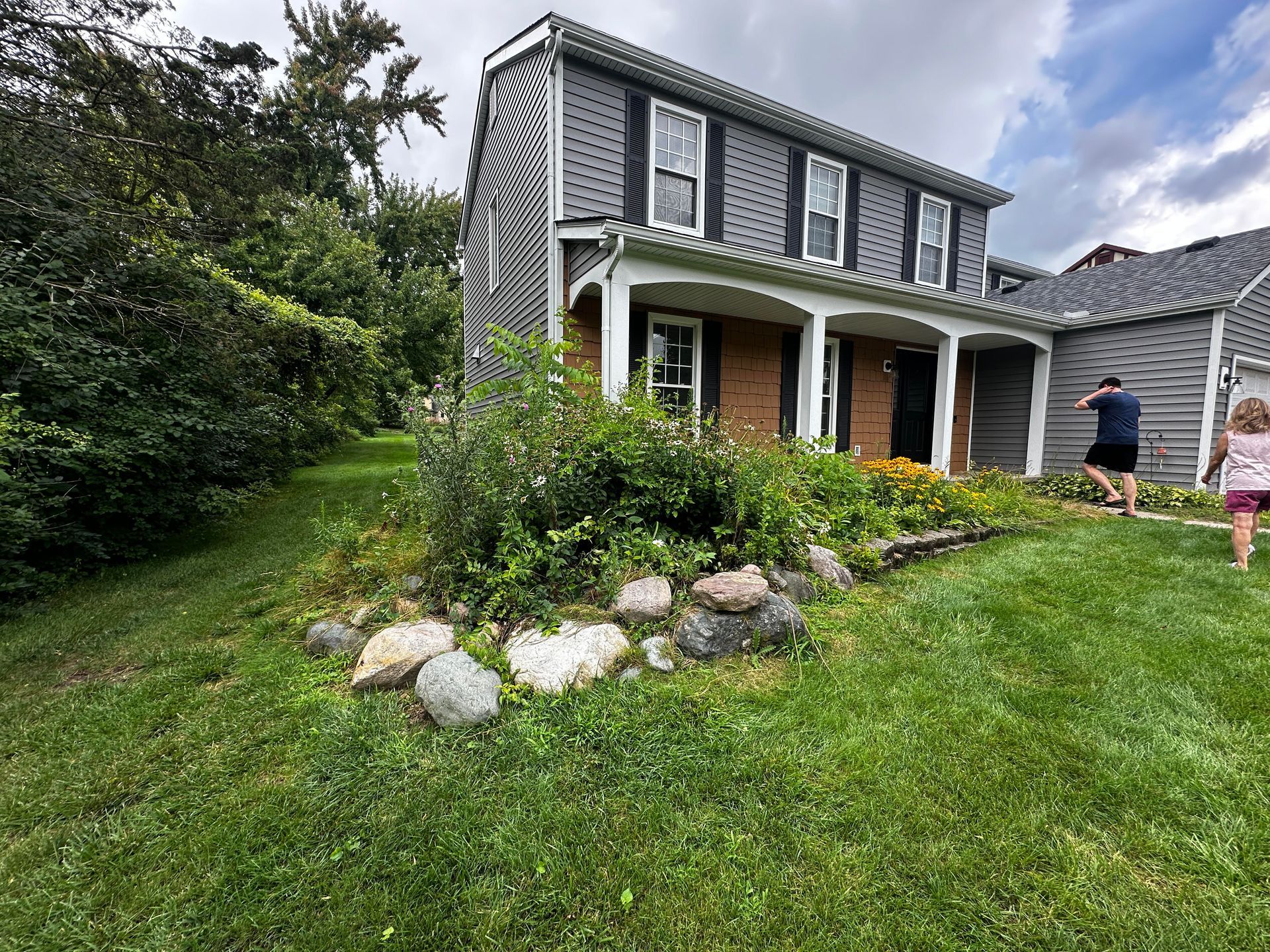 A man and a girl are running in front of a house.