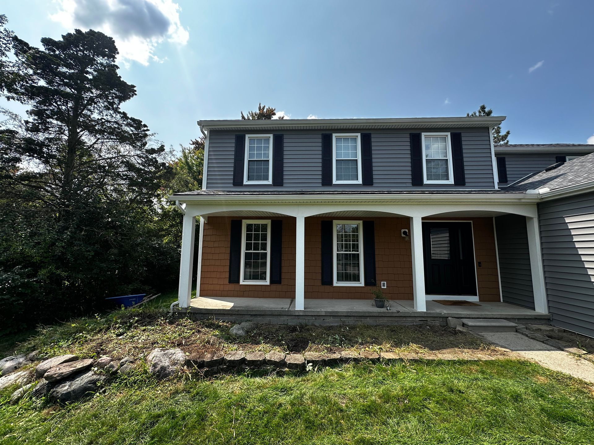 A brick house with a porch and black shutters