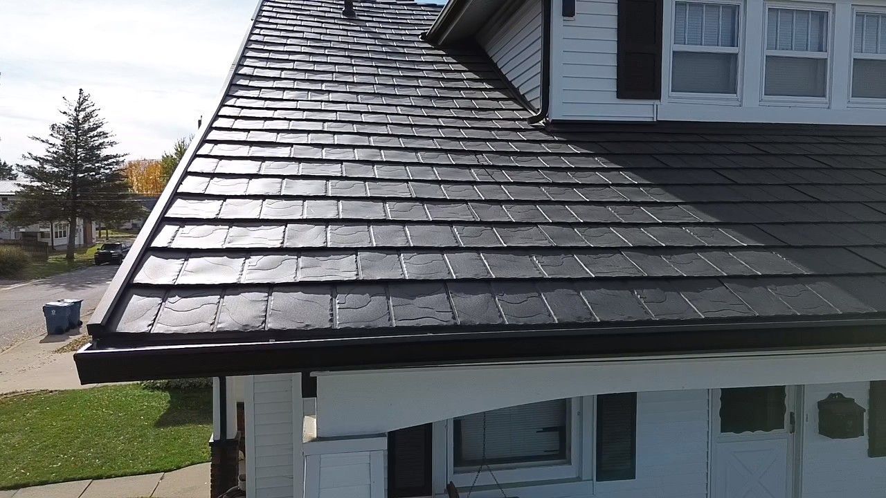 House roof with dark shingles and a white dormer over a front porch, viewed from the side
