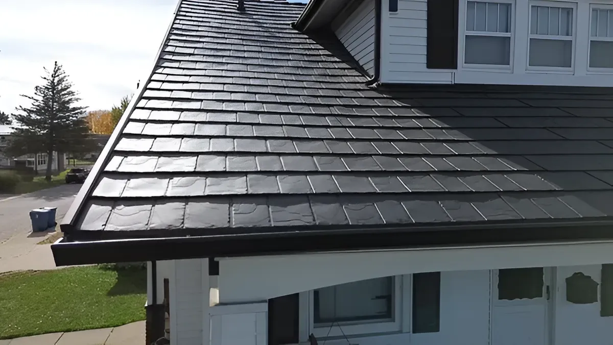 House roof with dark gray shingles and a white dormer, viewed from the side outdoors