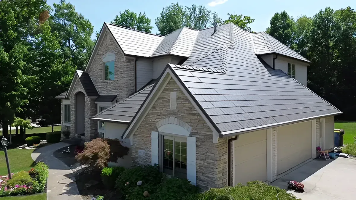 Suburban two-story stone and siding house with gray roof, driveway, and trees in front