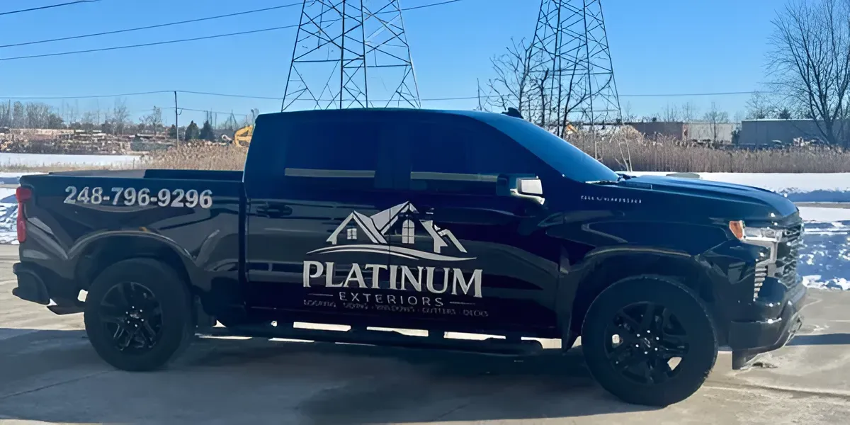 Black Platinum truck with company logo and phone number parked outdoors on a sunny day