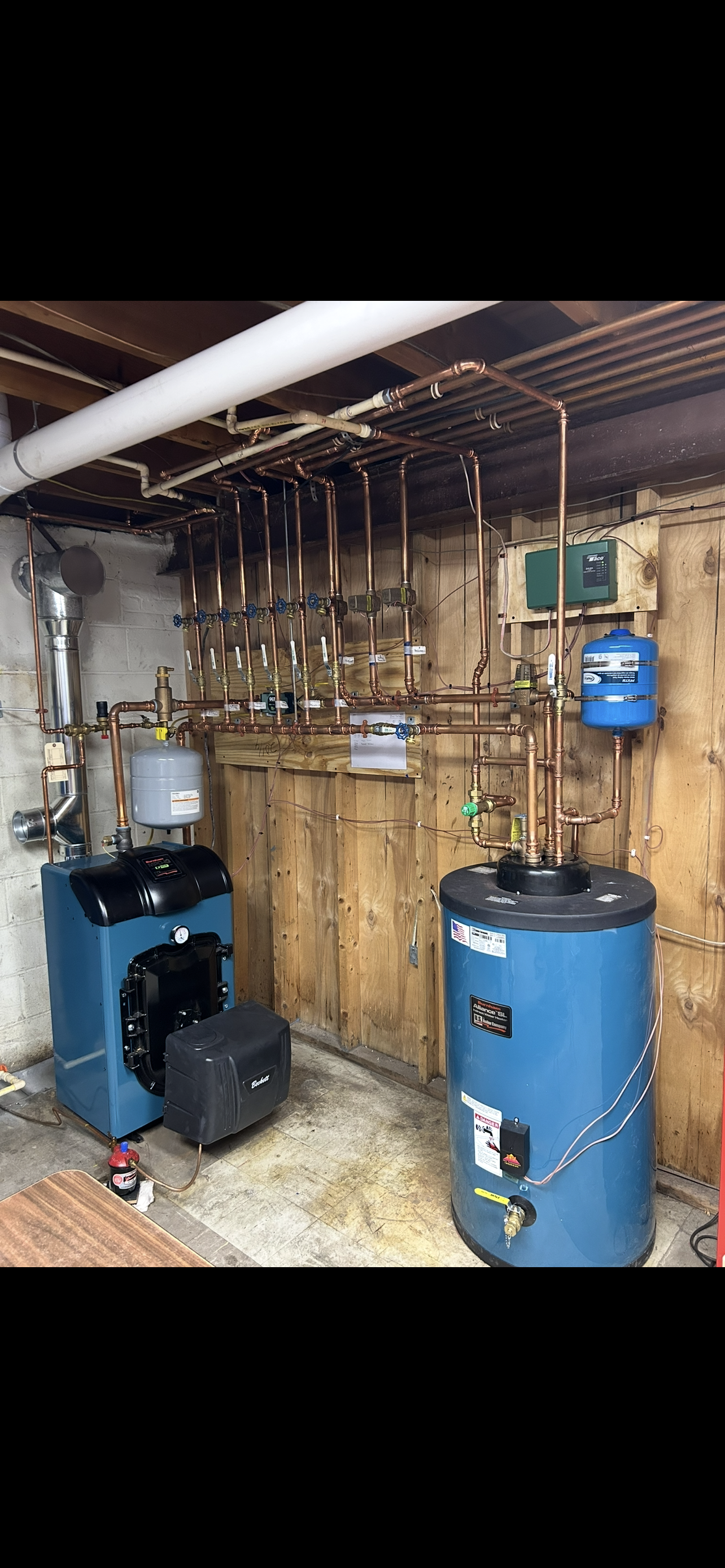 Laundry room with washing machine, water heater, shelves with cleaning supplies, and a sink.