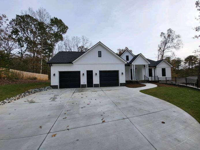 A white house with black garage doors and a concrete driveway