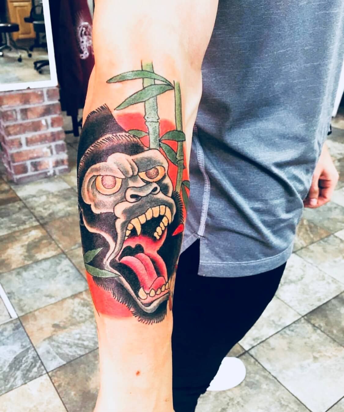 A man has a tattoo of a gorilla and bamboo on his arm