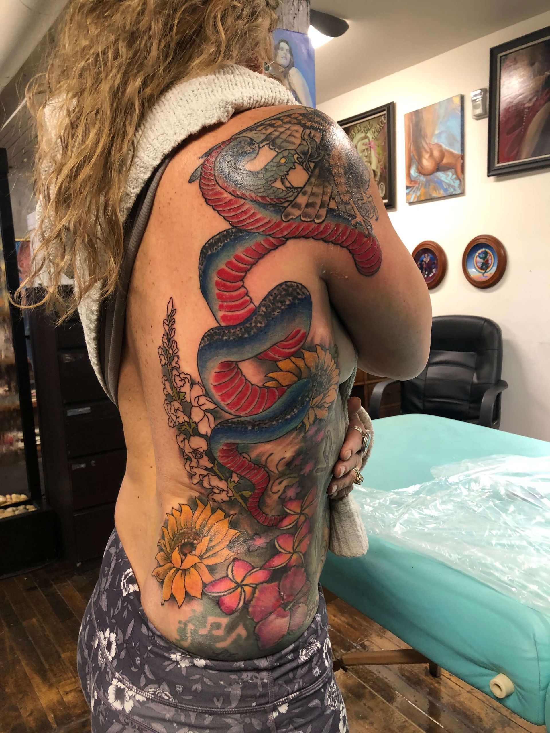 A woman has a tattoo of a snake on her back.