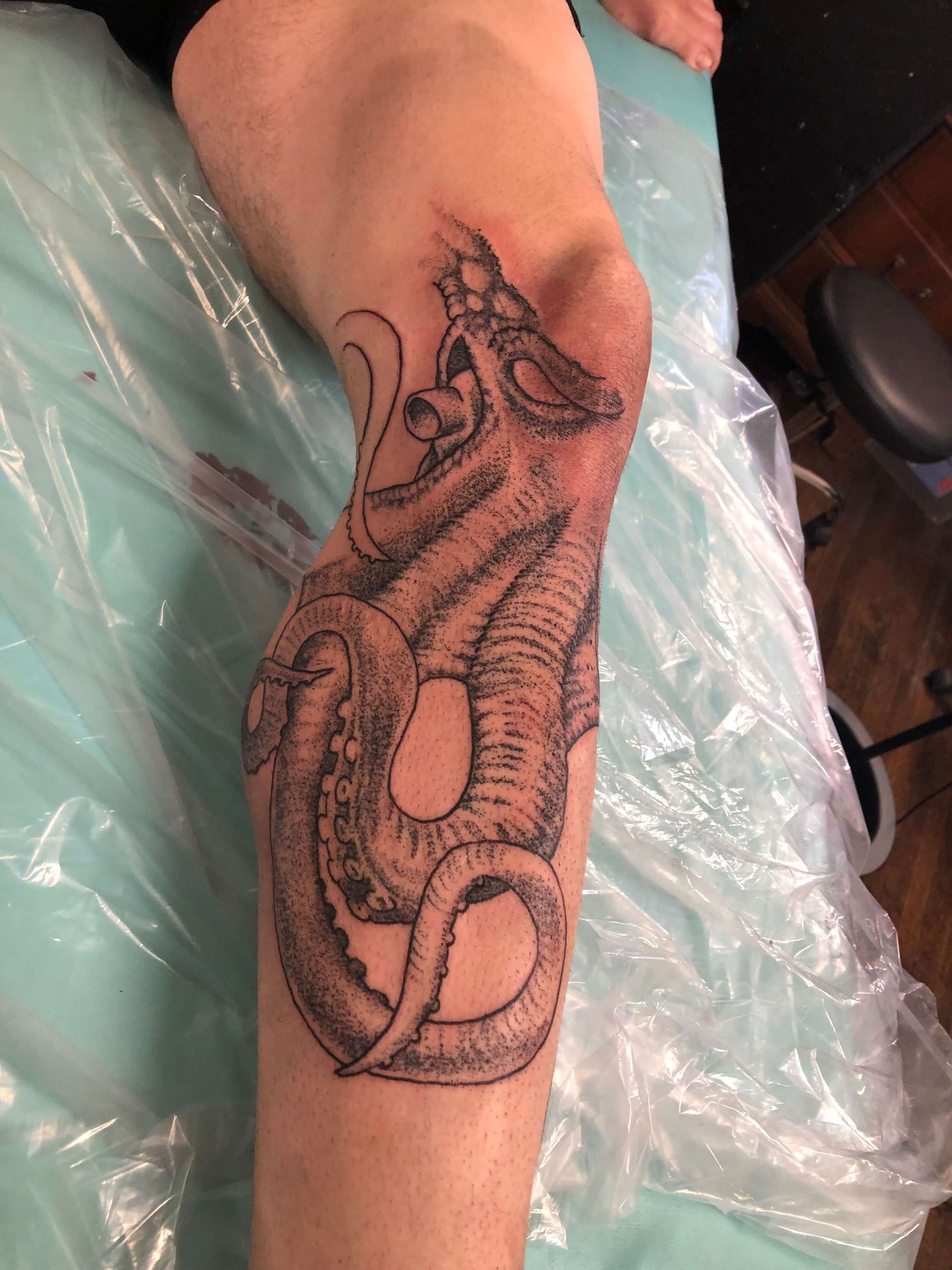 A person has a tattoo of a dragon on their leg.