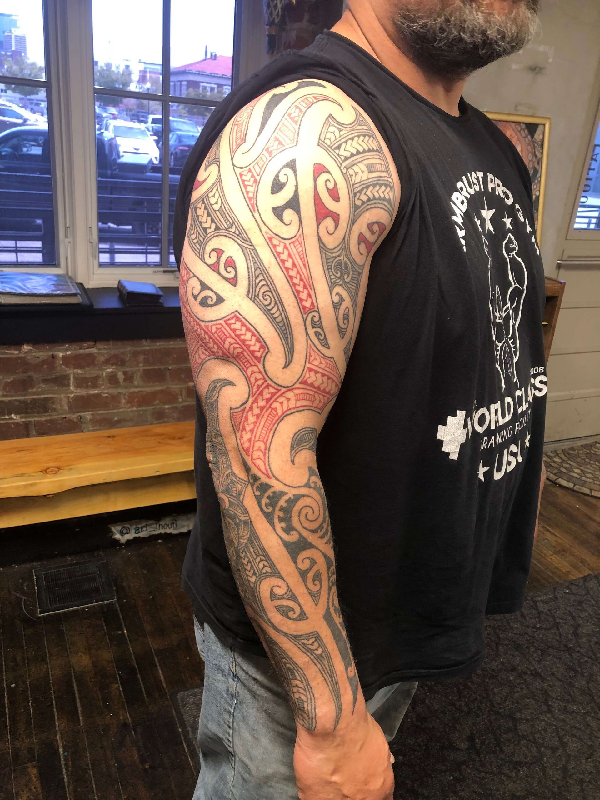 A man with a tattoo on his arm is wearing a black tank top