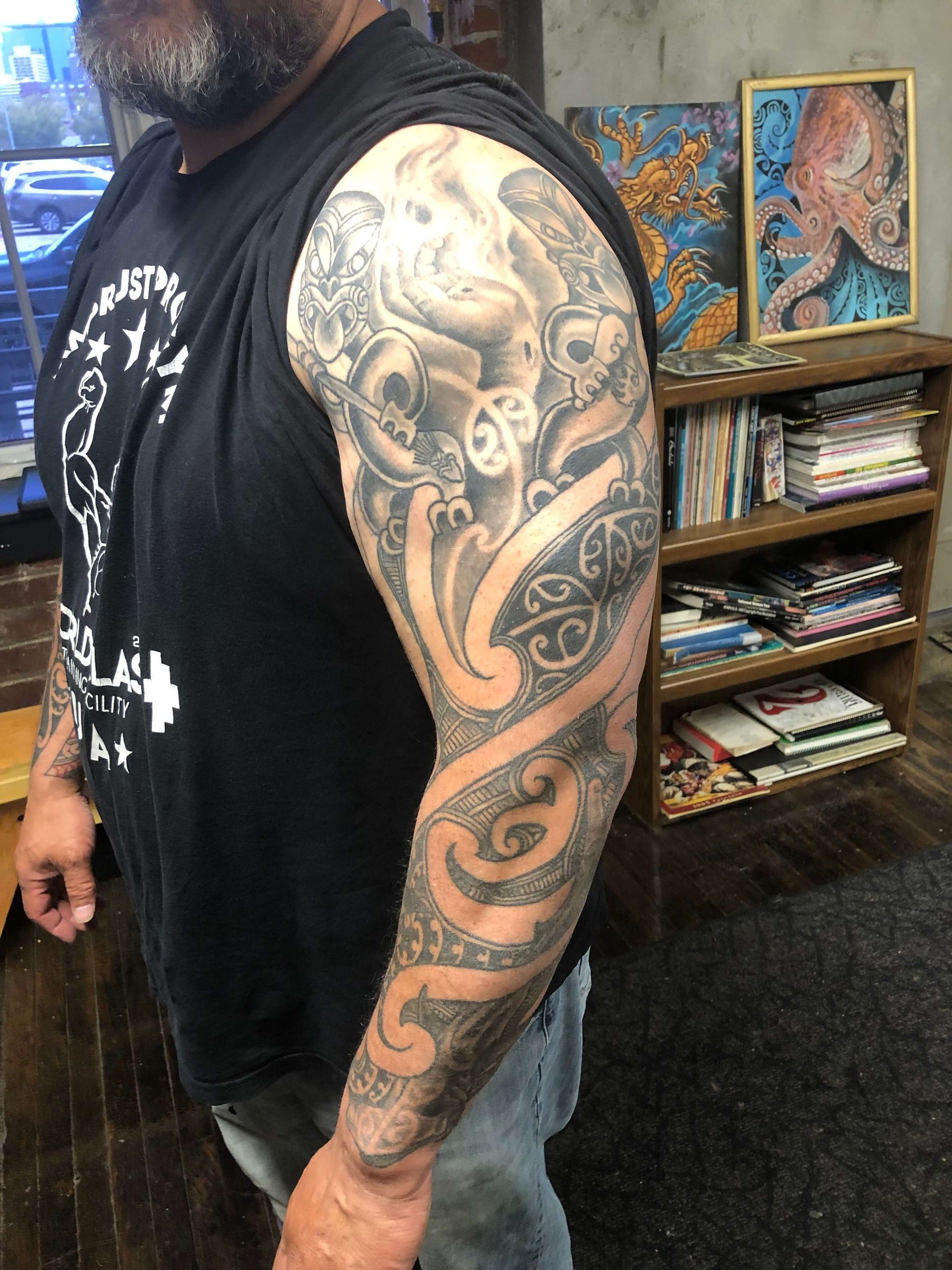 A man with a tattoo on his arm is wearing a black tank top