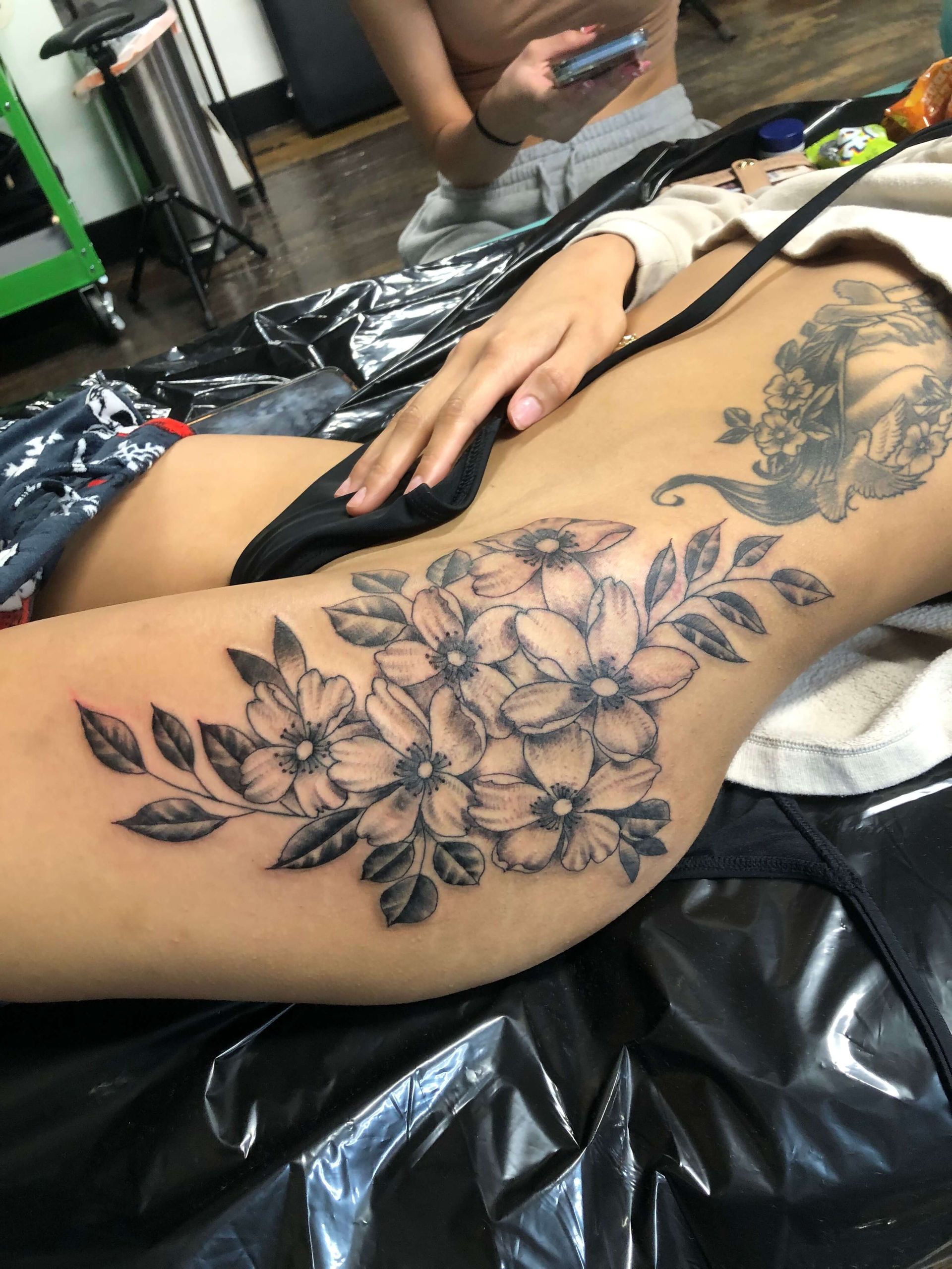 A woman has a tattoo of flowers on her thigh.