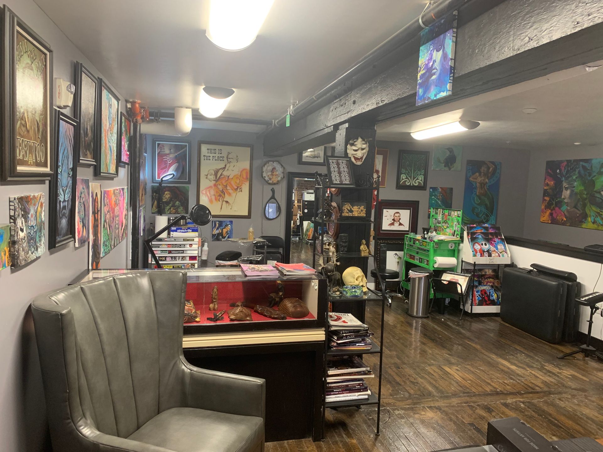 Tattoo studio interior with art, chair, display case, and equipment.
