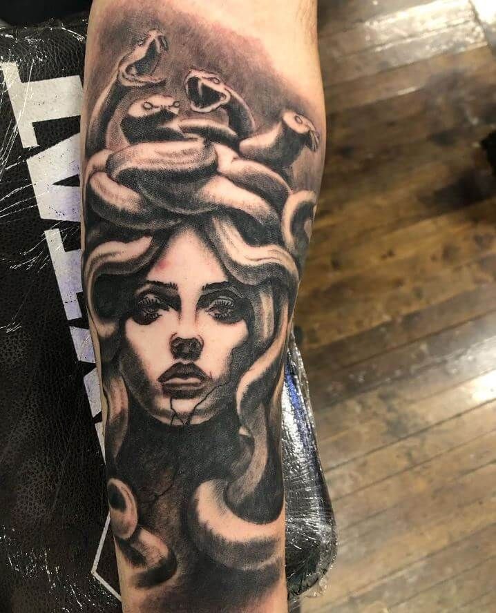 A black and white tattoo of a woman with snakes on her head.
