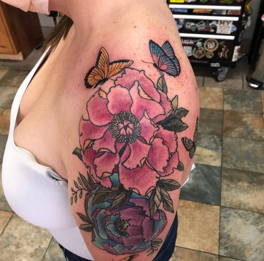 A woman has a tattoo of flowers and butterflies on her shoulder