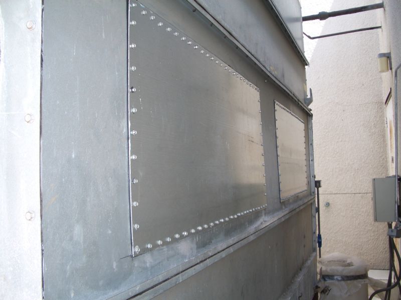 Exterior of a metallic structure with riveted panels; angled view in an outdoor setting.