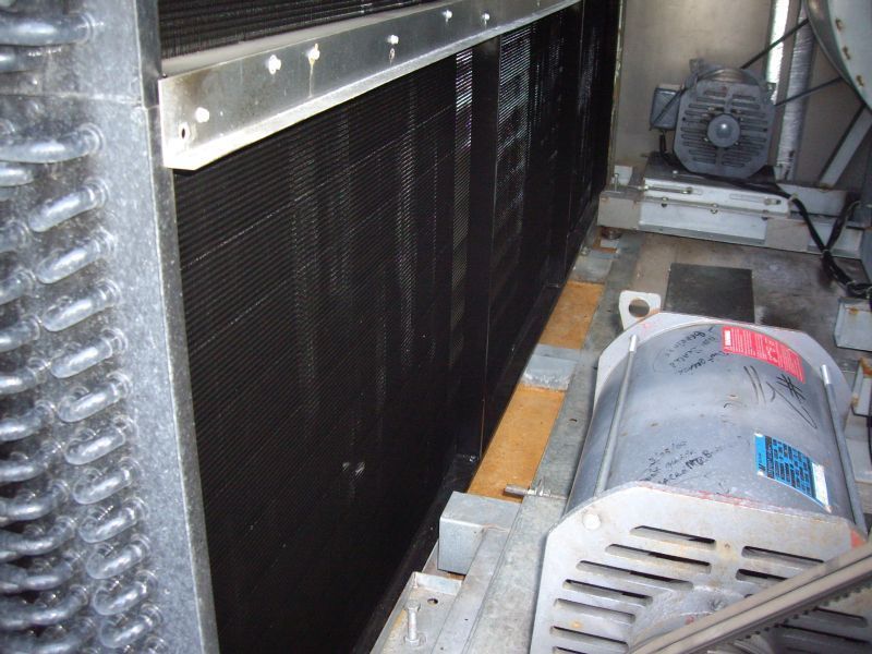 Inside view of a large industrial air conditioning unit with black cooling fins, metal frame, and electric motor.