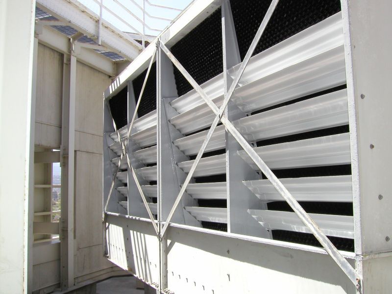 White industrial cooling tower with angled, slatted vents.