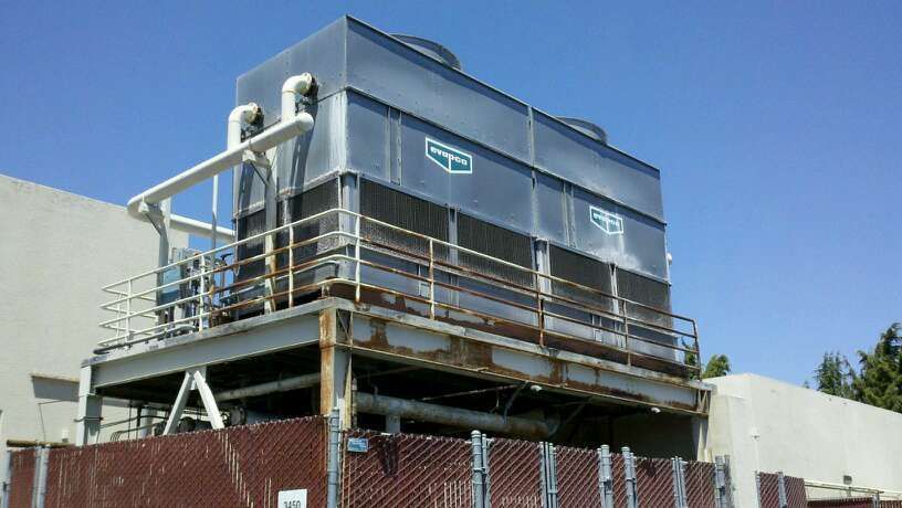 Large industrial cooling tower on a metal platform, outdoors against a blue sky.