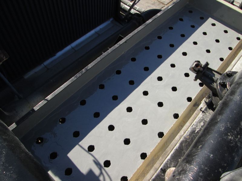 Gray metal tray with evenly spaced black holes, next to a radiator.