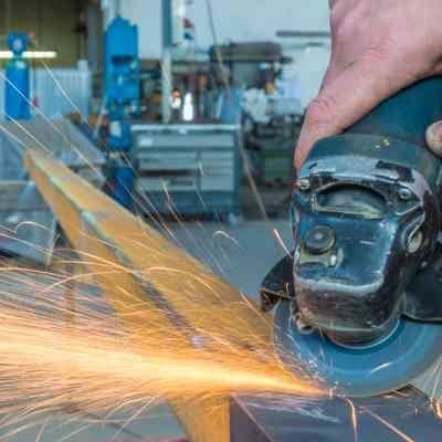 A person is using a grinder to cut a piece of metal.