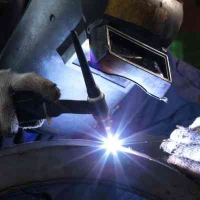 A man is welding a piece of metal with a torch.