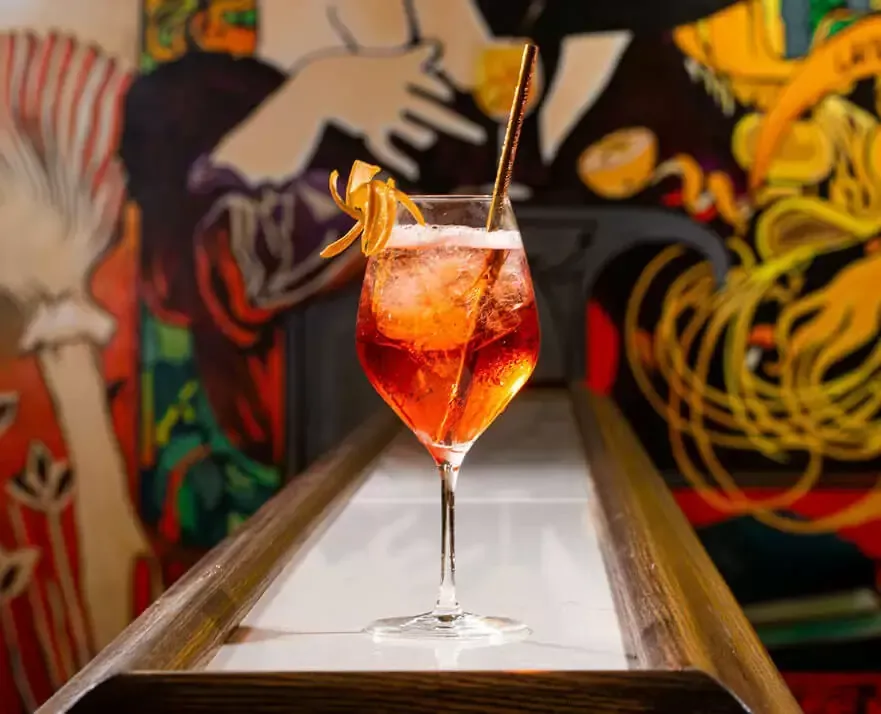 A close up of a cocktail in a wine glass on a table.