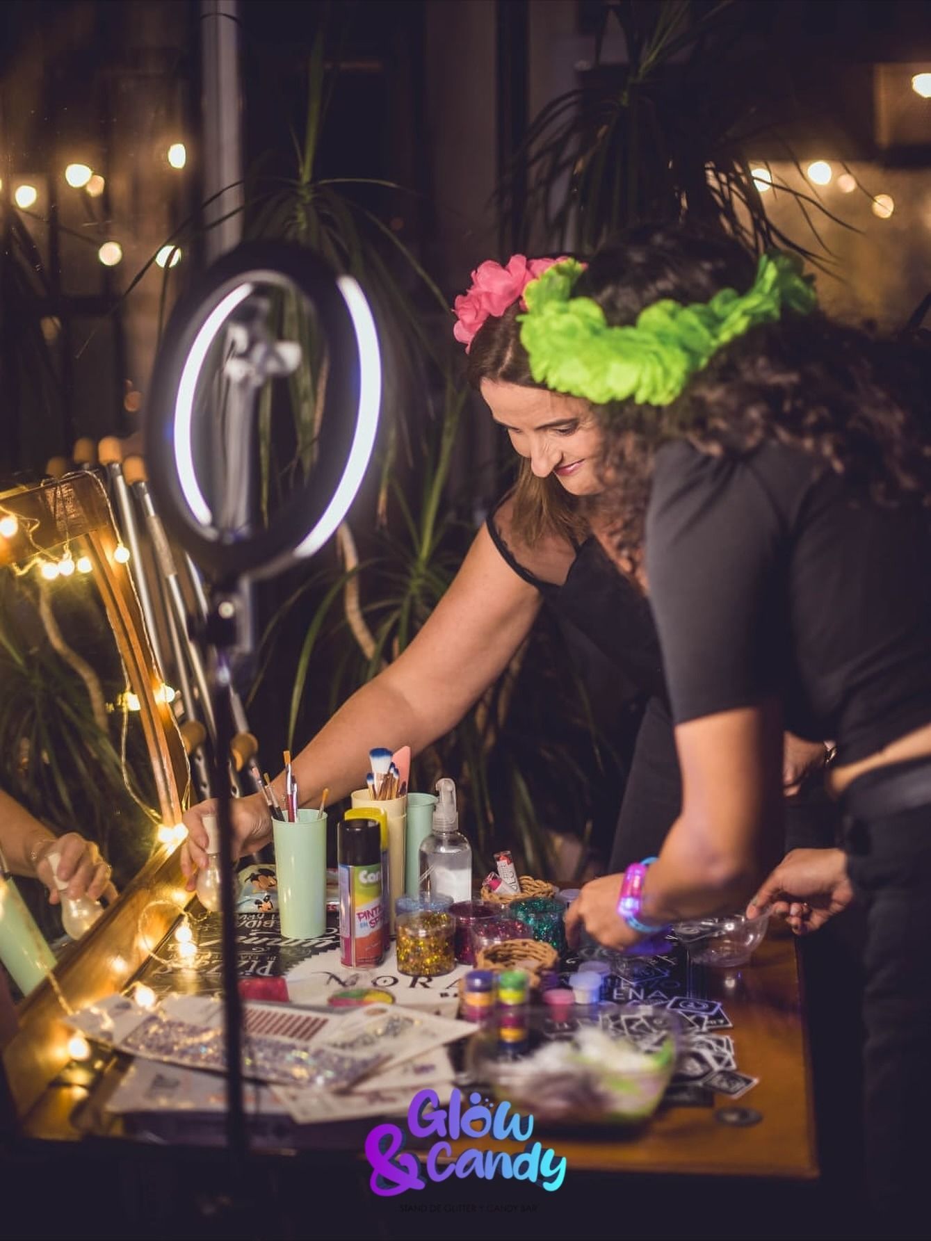 Una persona decora una mesa con pintura y luces de neón, luciendo una corona de flores en un evento de Glow Sunday.