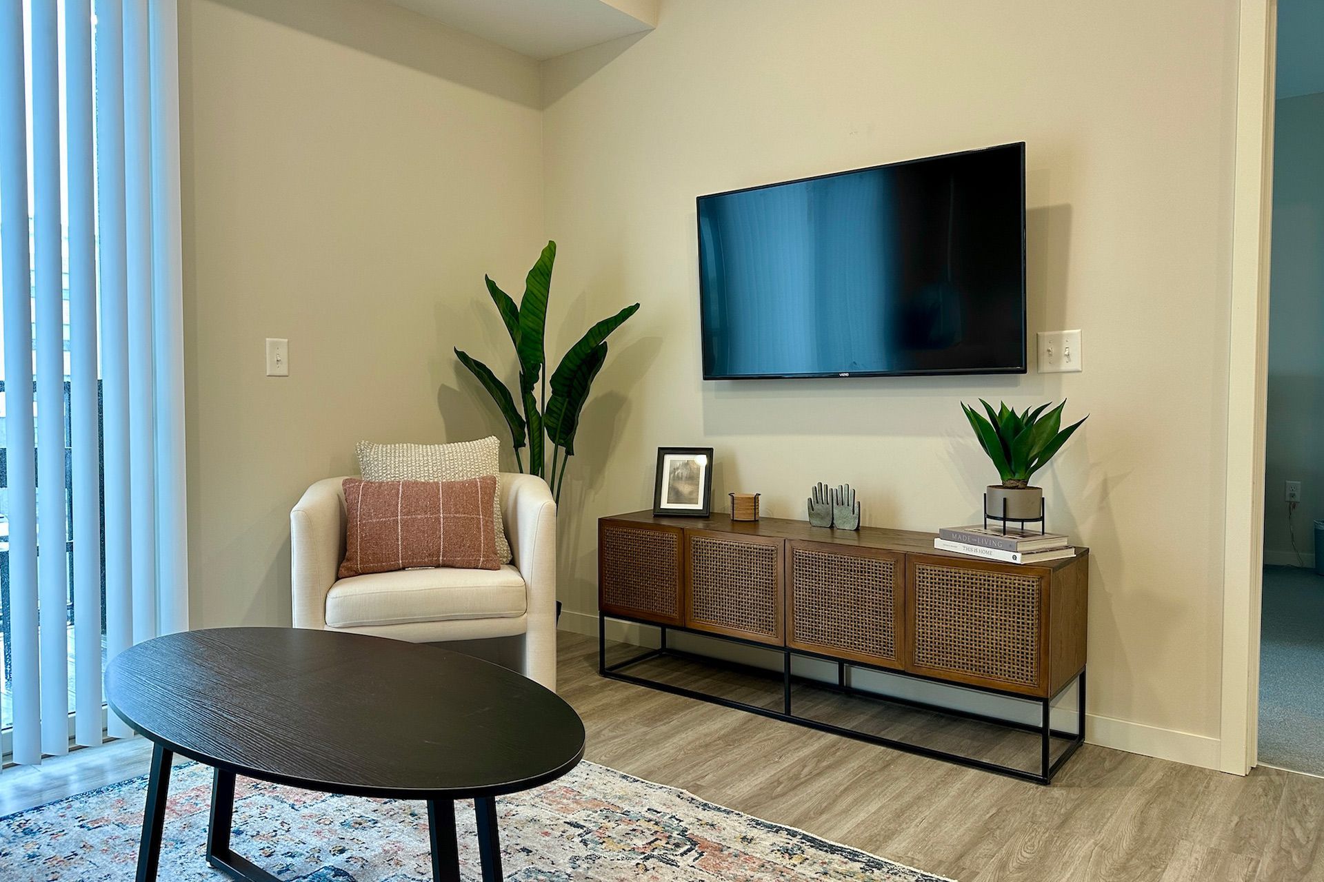 Living room with a mounted TV, armchair, coffee table, and console table with a potted plant.