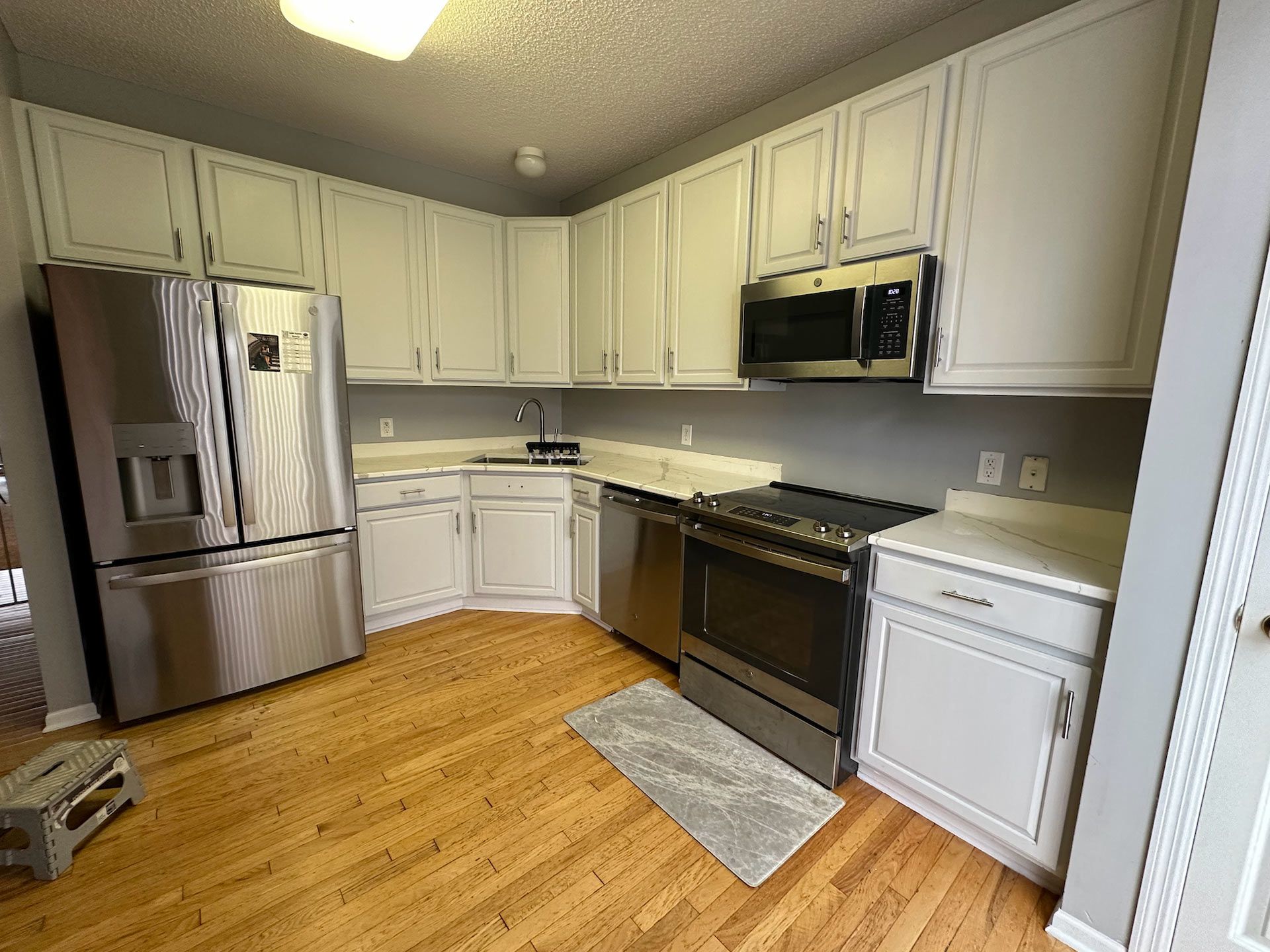 Kitchen with light-colored cabinets, stainless steel appliances, and wooden flooring.
