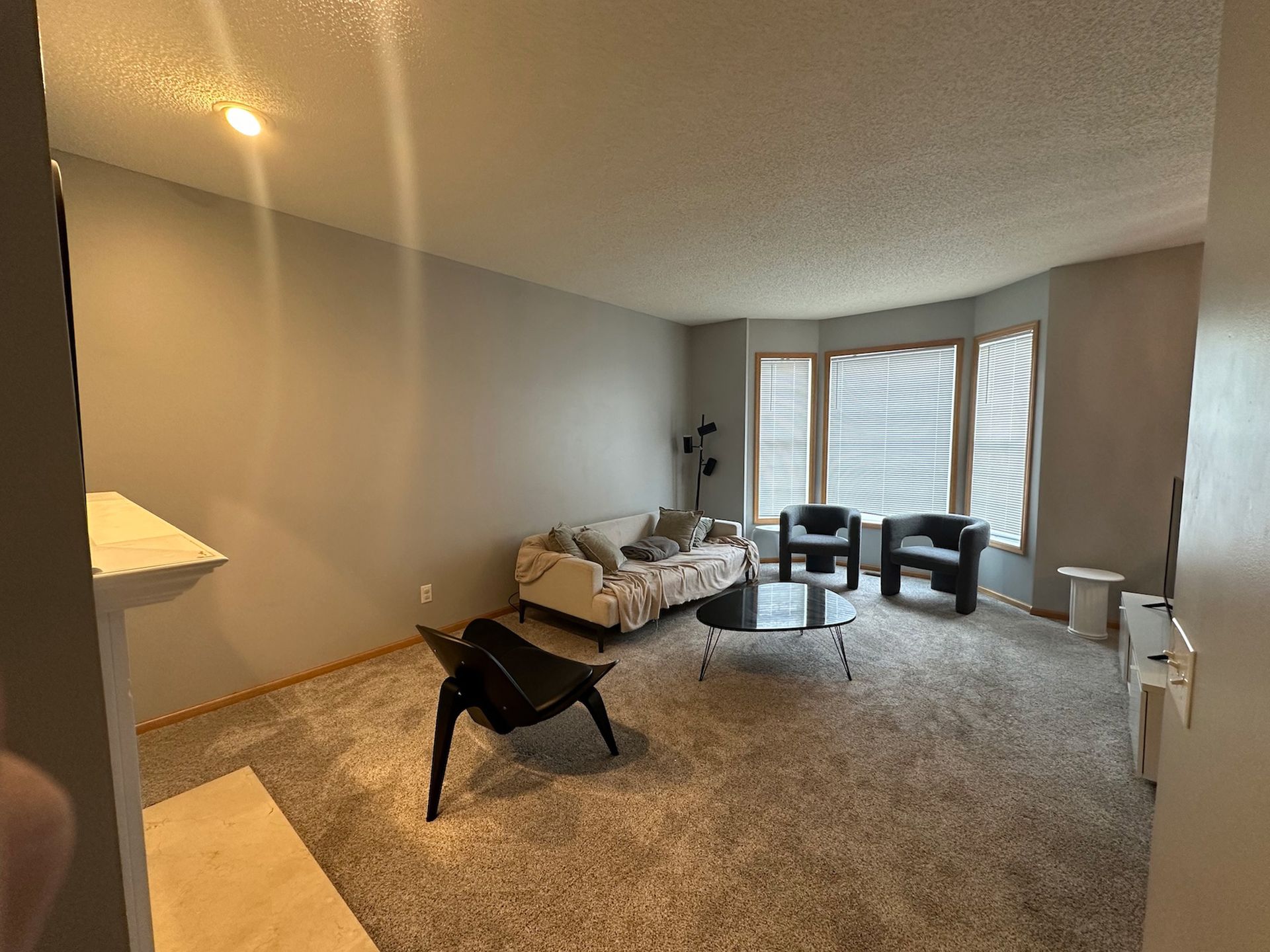 Living room with gray walls, sofa, chairs, coffee table, and large window.