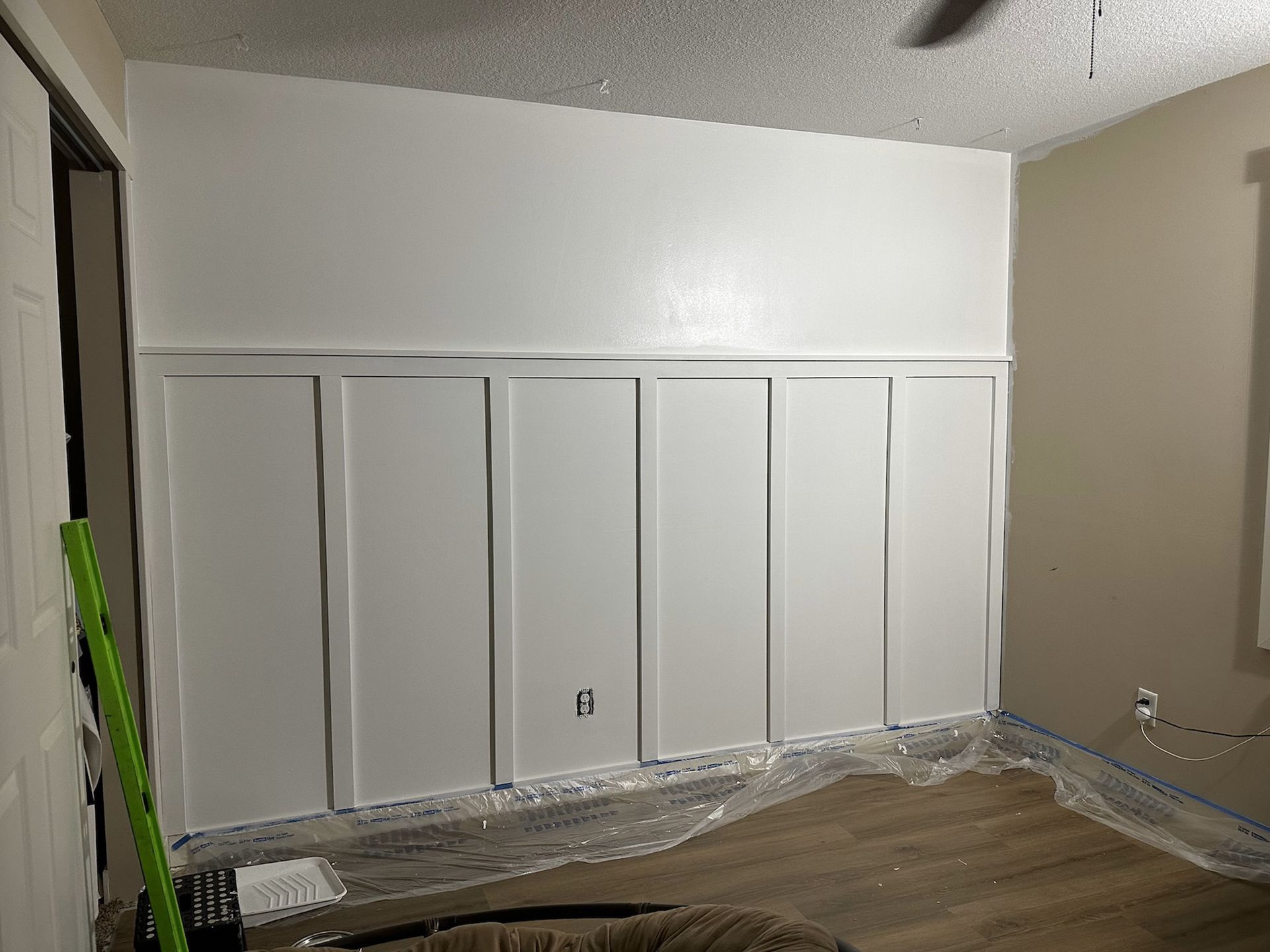 White paneled wall with a section painted; room under renovation.