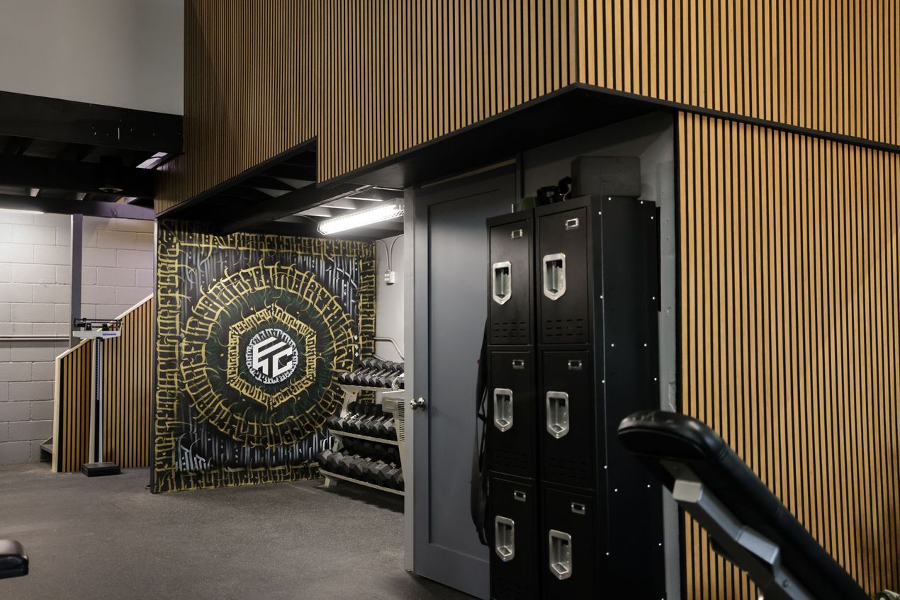 Gym interior with black lockers, wooden paneling, and a mural. Gym interior with black lockers, wooden paneling, and a mural.