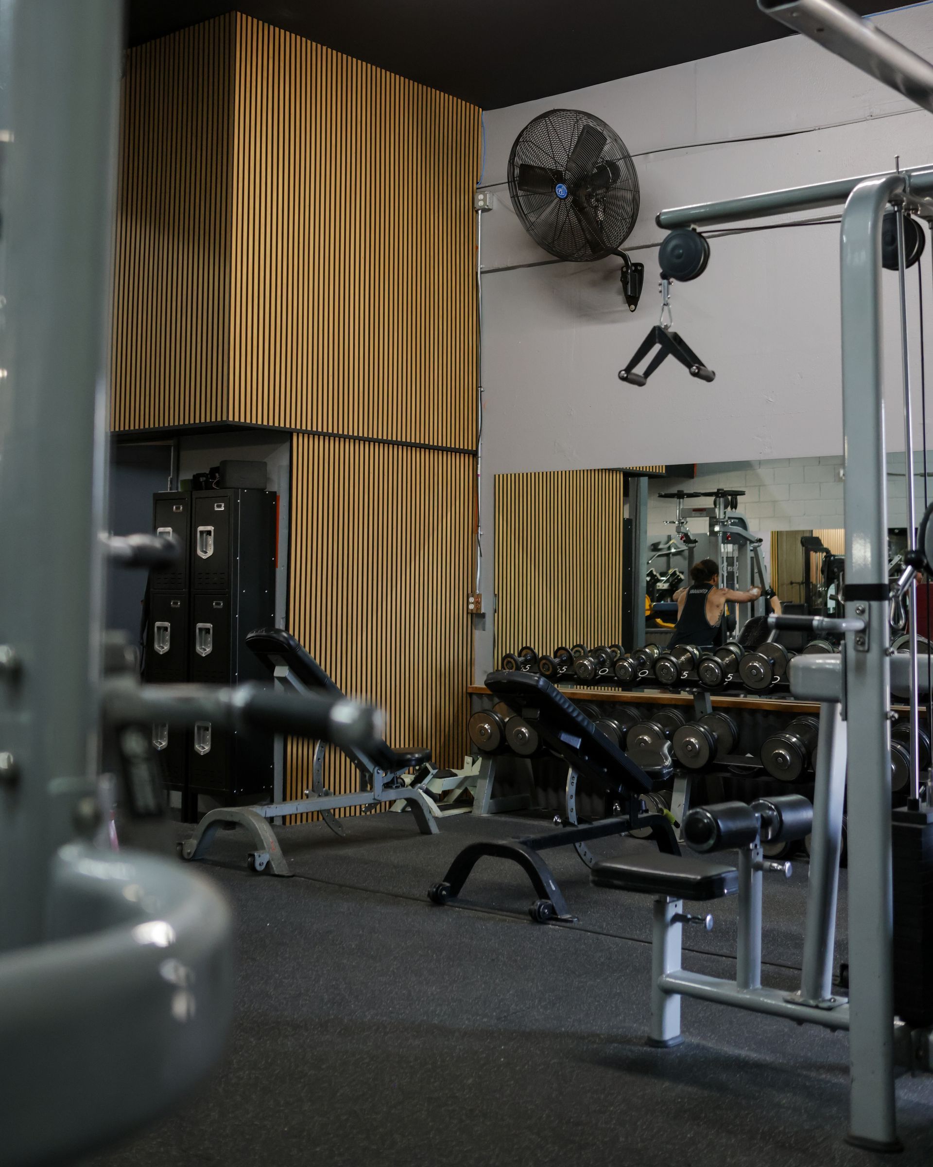 Gym interior with exercise machines, weights, and a locker area.