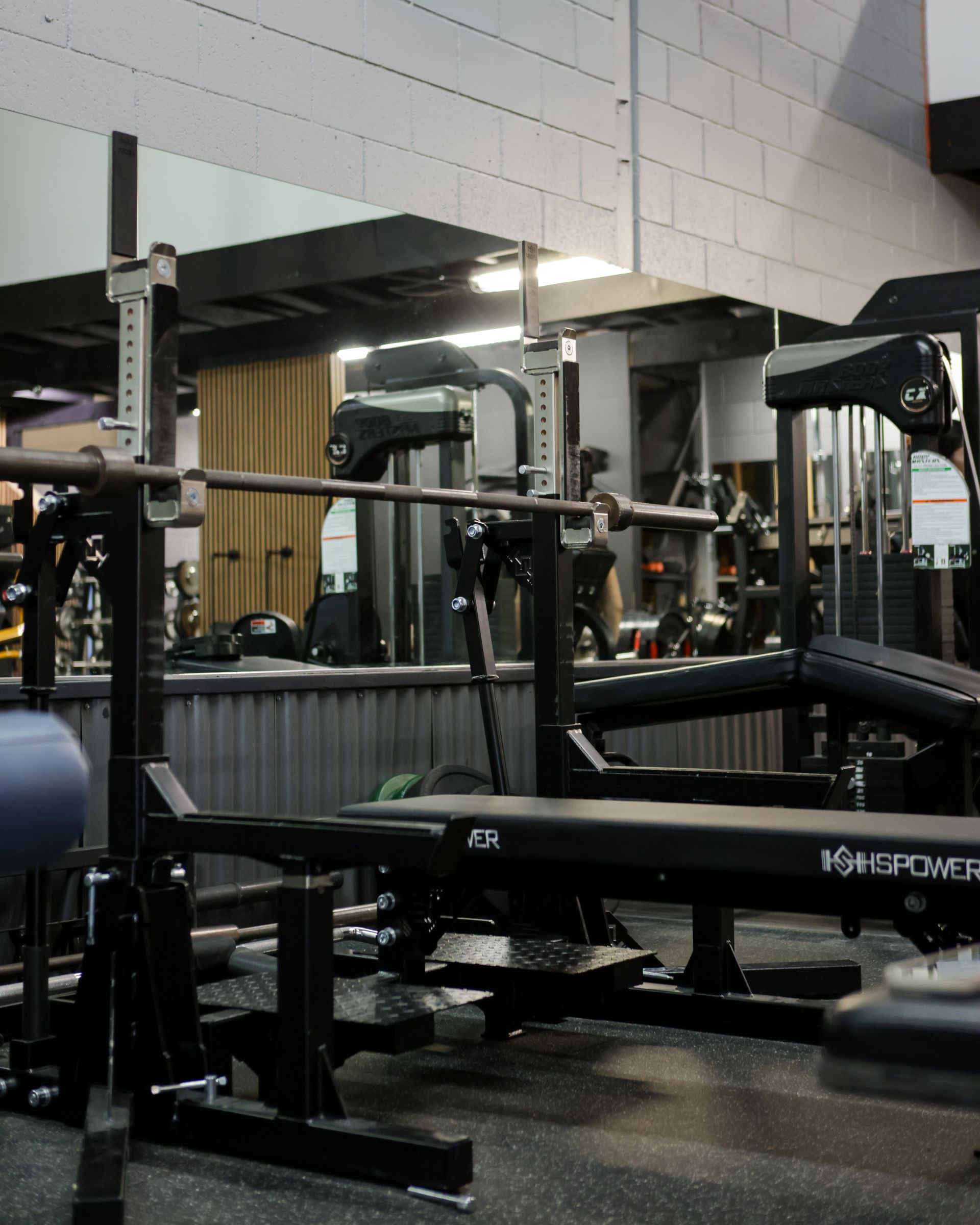Weightlifting bench with barbell and squat rack in a gym setting. Weightlifting bench with barbell and squat rack in a gym setting.