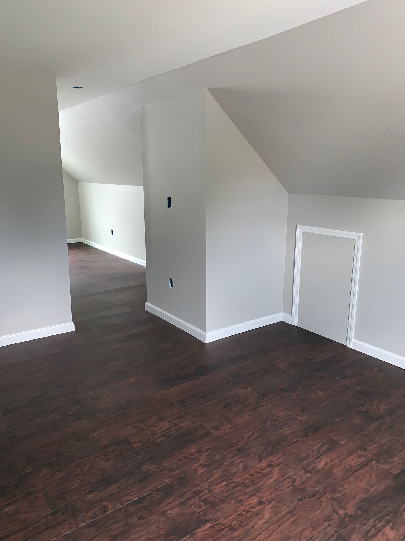 A man is standing on a ladder painting a wall with a paint roller.