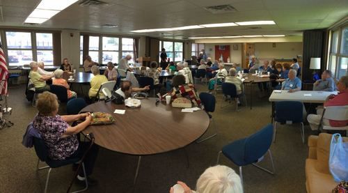 A large room filled with people sitting at tables and chairs.