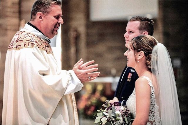 priest is speaking to bride and groom