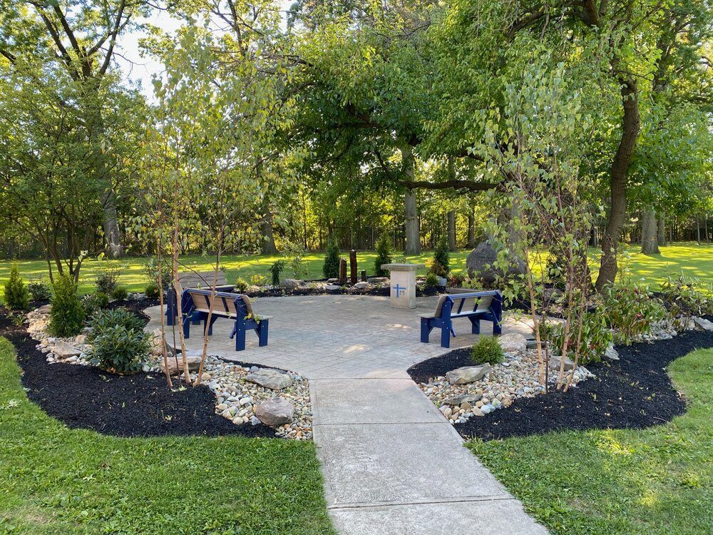 A concrete walkway leading to a picnic area in a park.