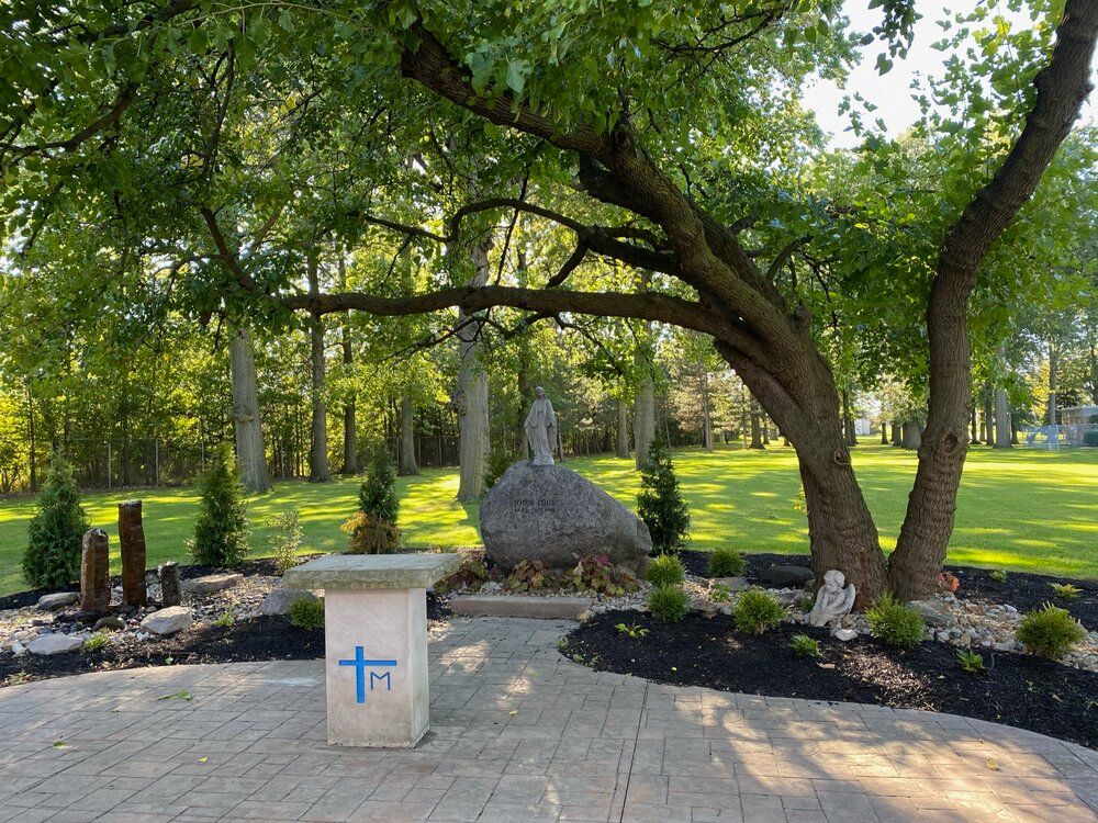 There is a table with a cross on it in the middle of a park.