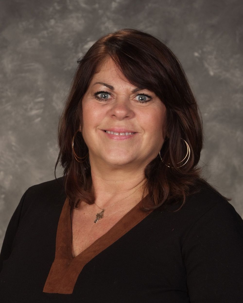 A woman wearing a black shirt and a brown collar is smiling for the camera.