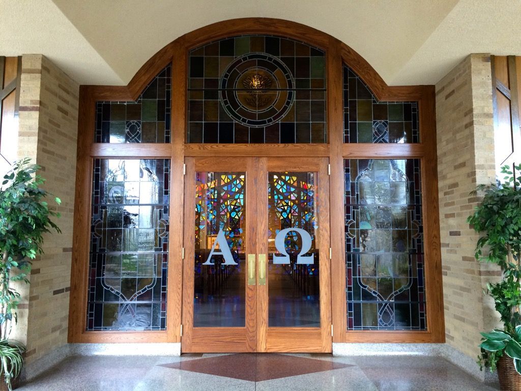A stained-glass window with the letters alpha and omega on it