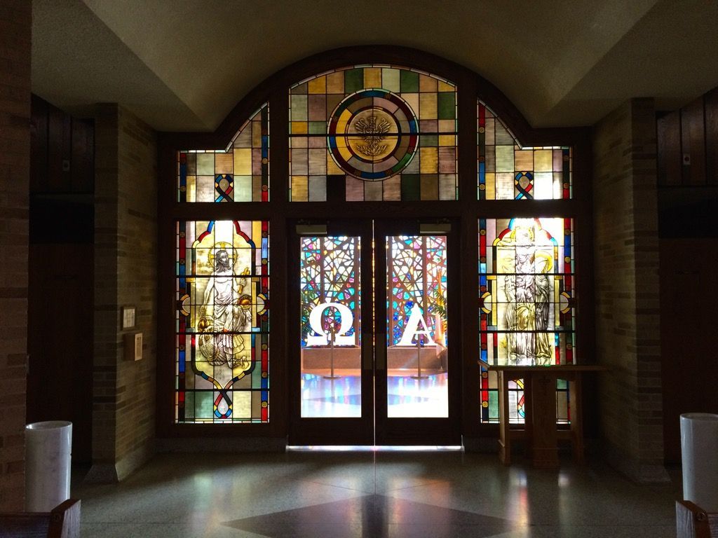 A stained-glass window with the letters omega and alpha on it