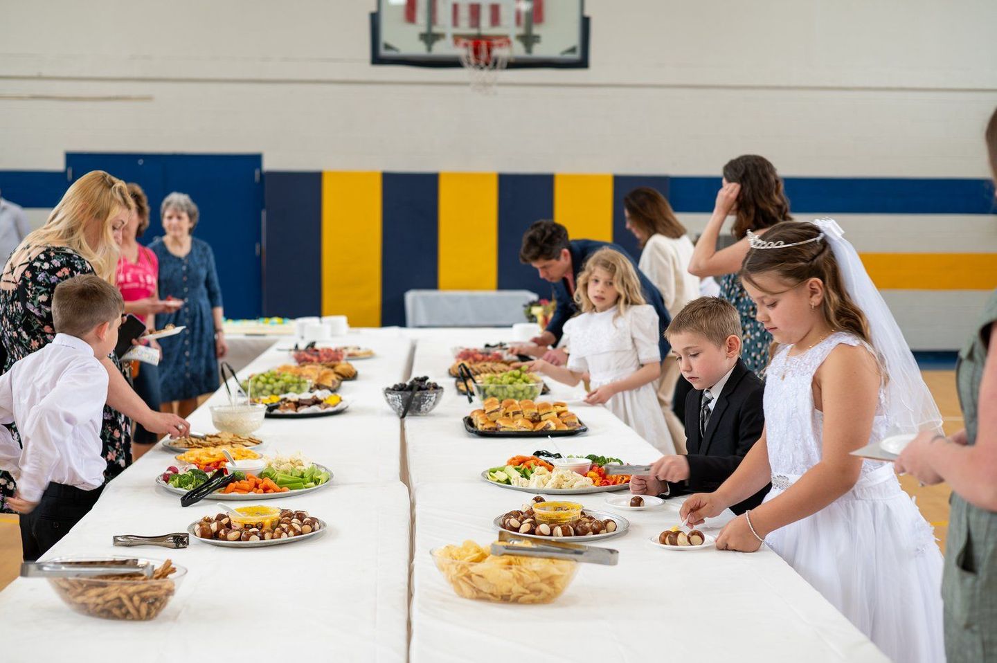 A group of children are sitting at a long table eating food.