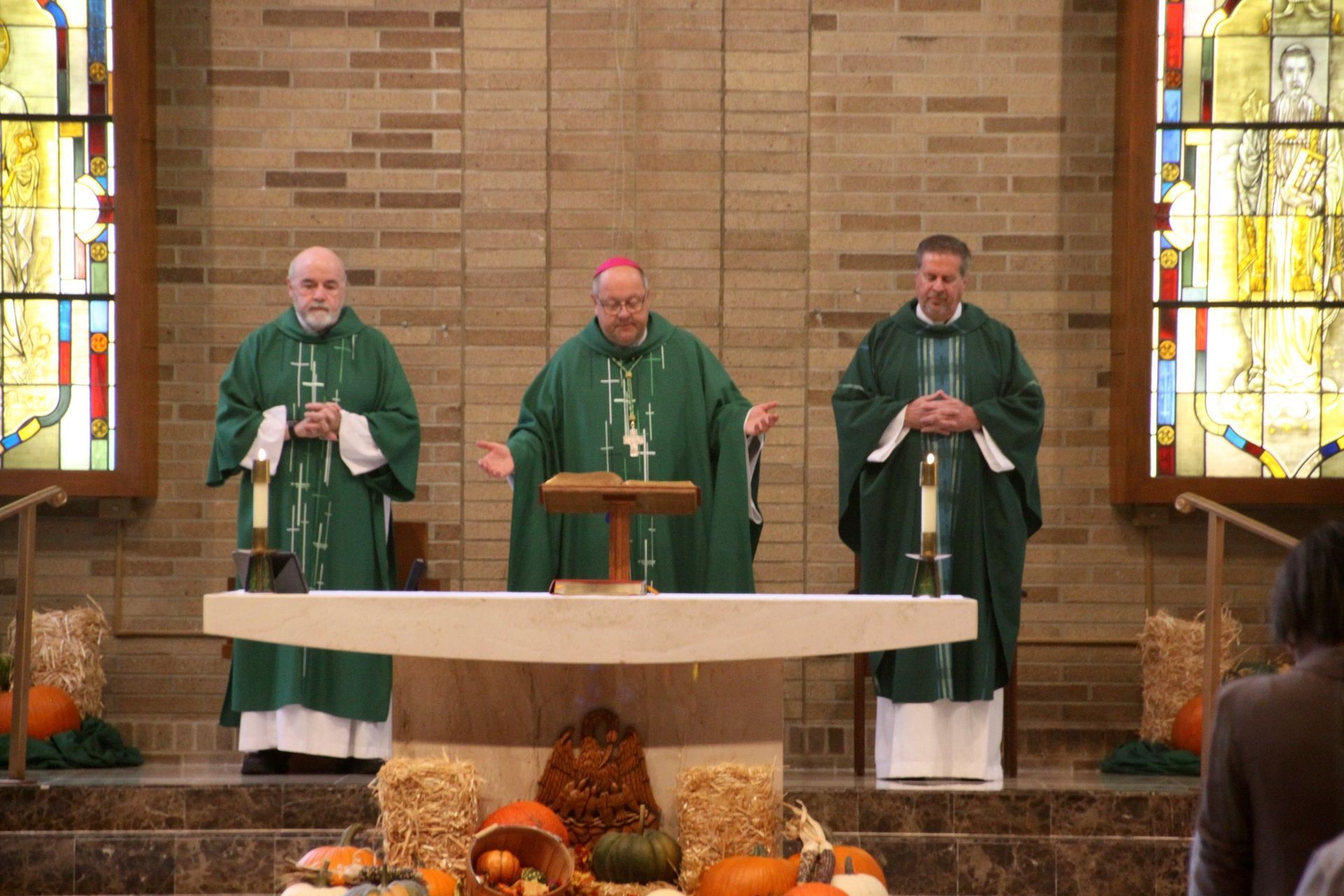 Three priests are standing in front of an altar in a church.
