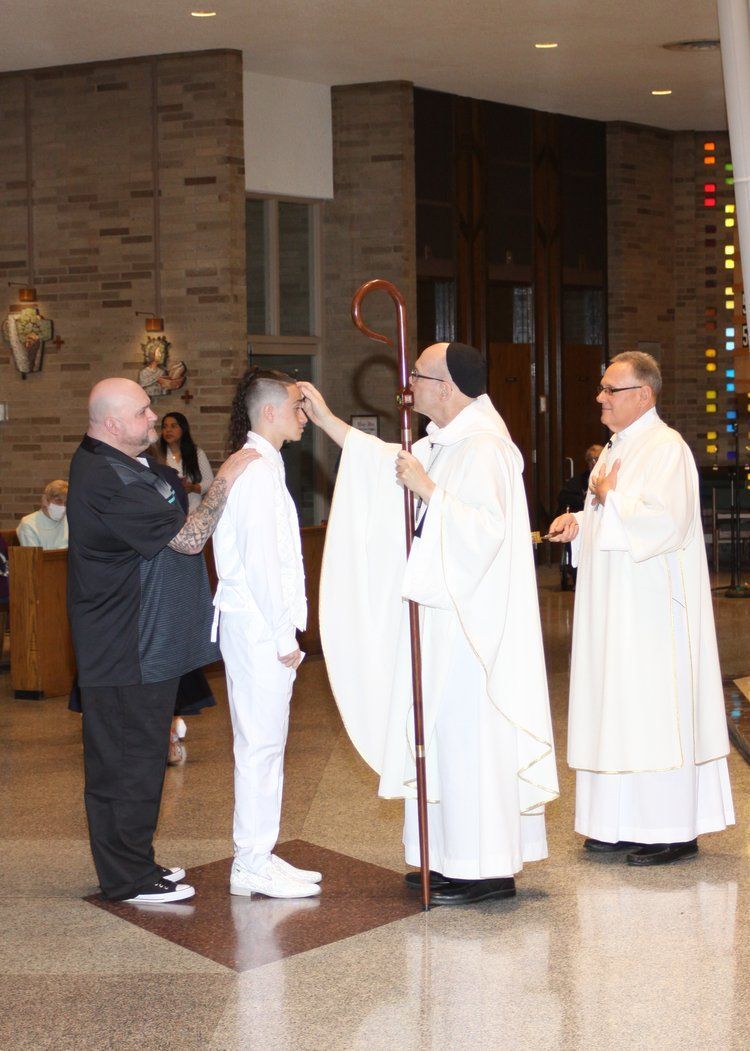 the bishop is blessing a youth