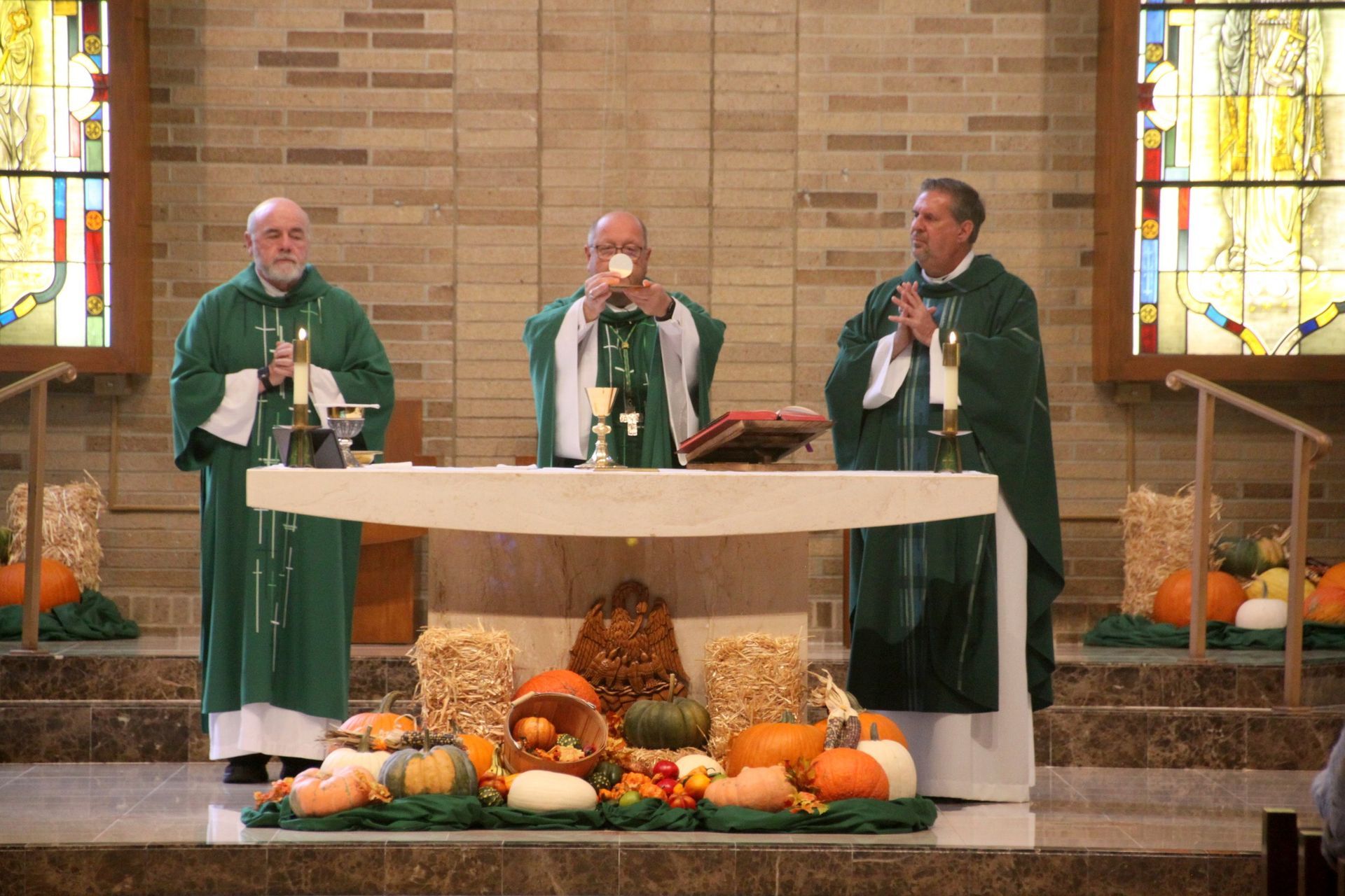 Three priests are standing at an altar in a church.