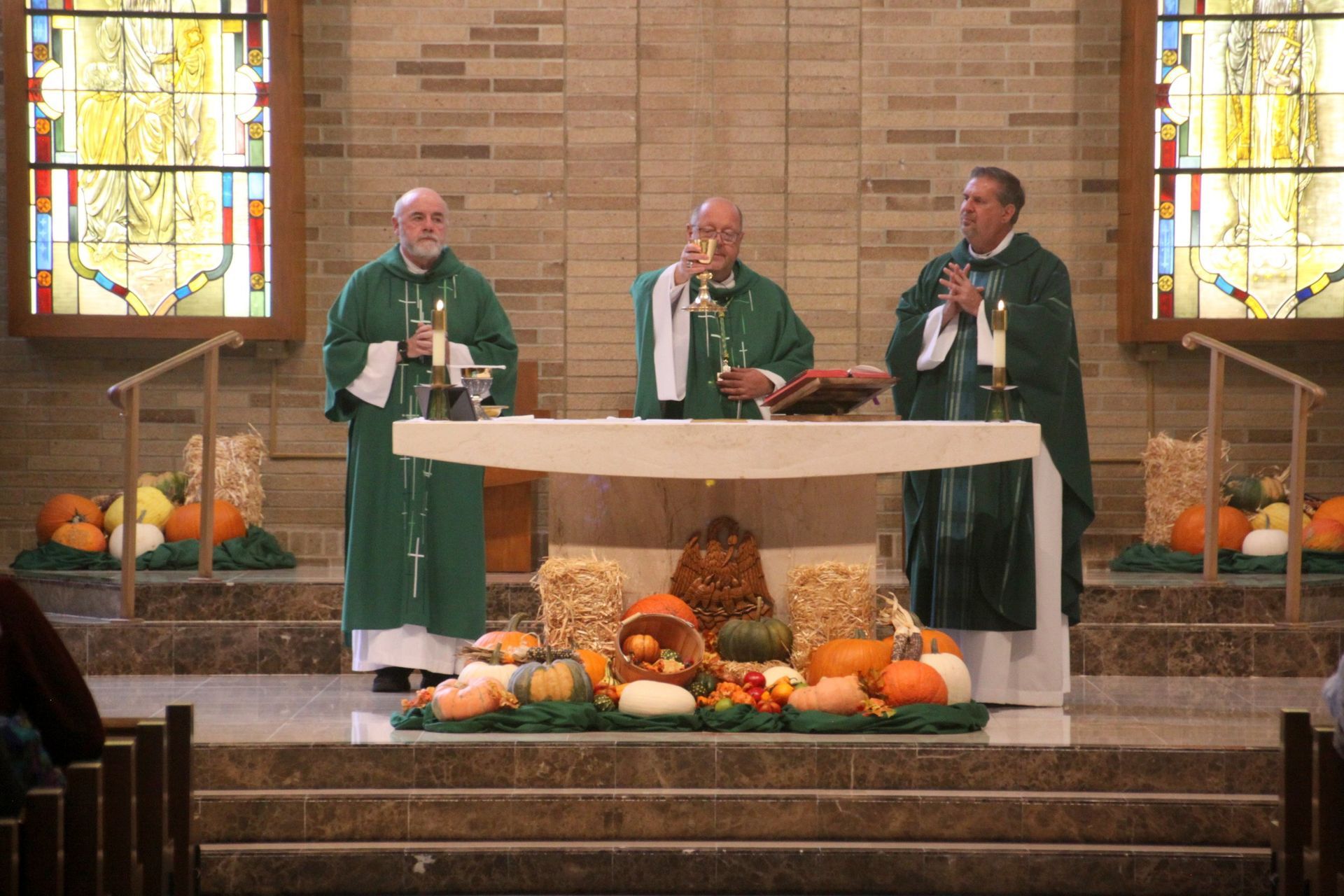 Three priests are standing at an altar 