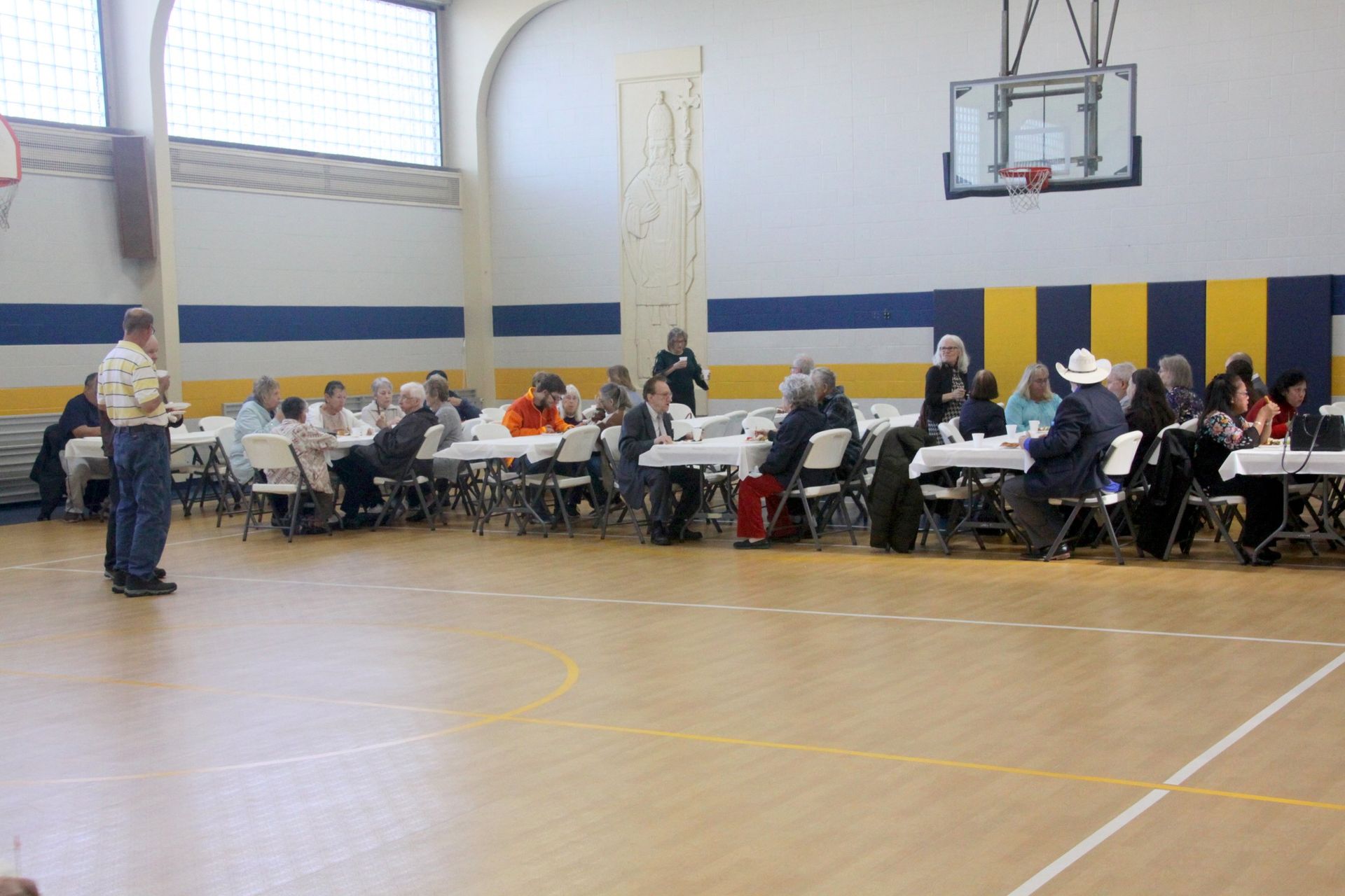 A group of people are sitting at tables in a gym